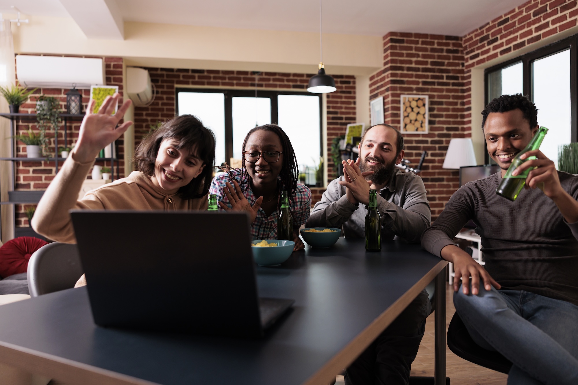 Multiethnic group of friends waving hand at online video call conference on laptop computer.