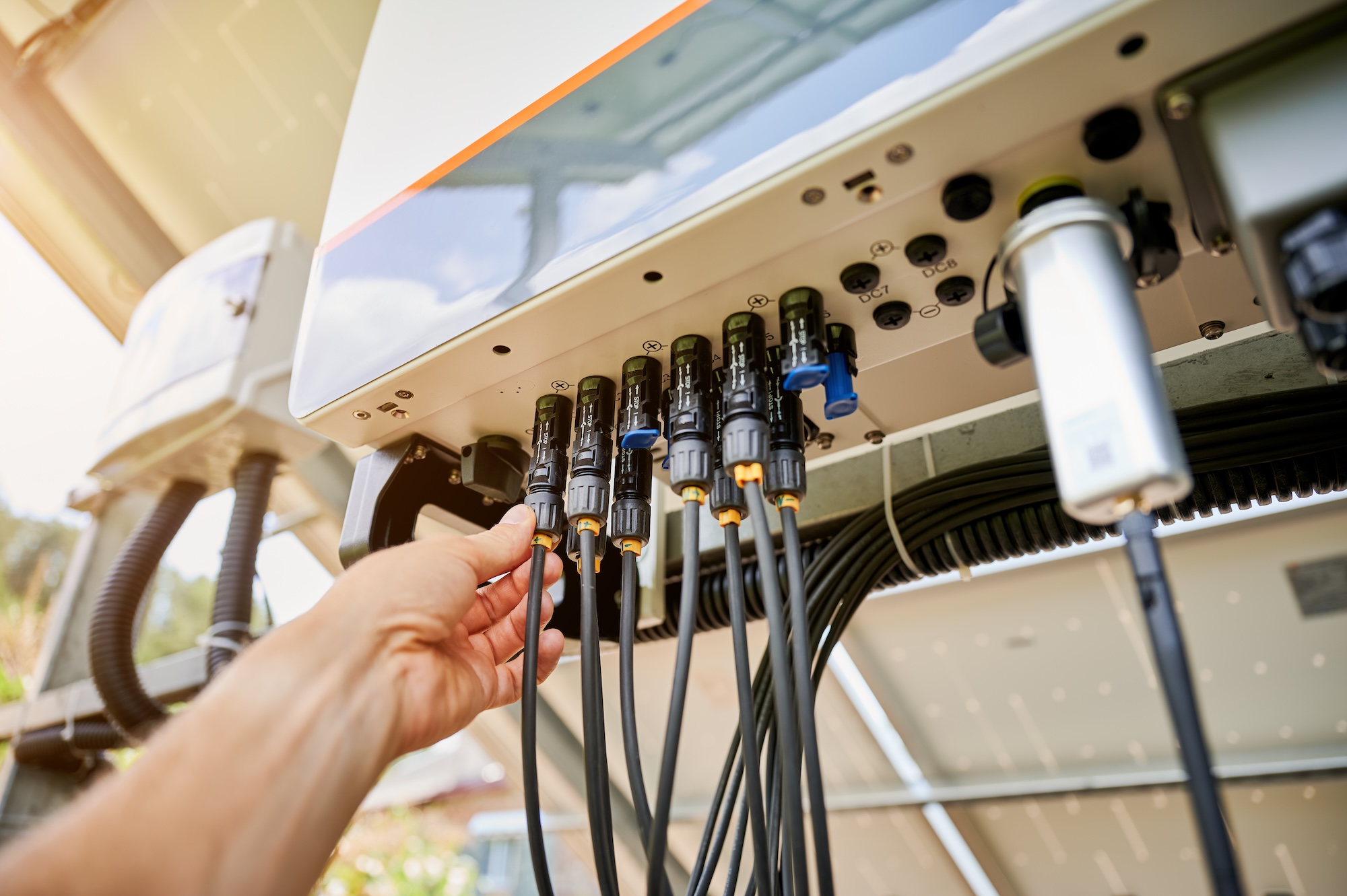 Professional worker connecting wires to solar inverter.